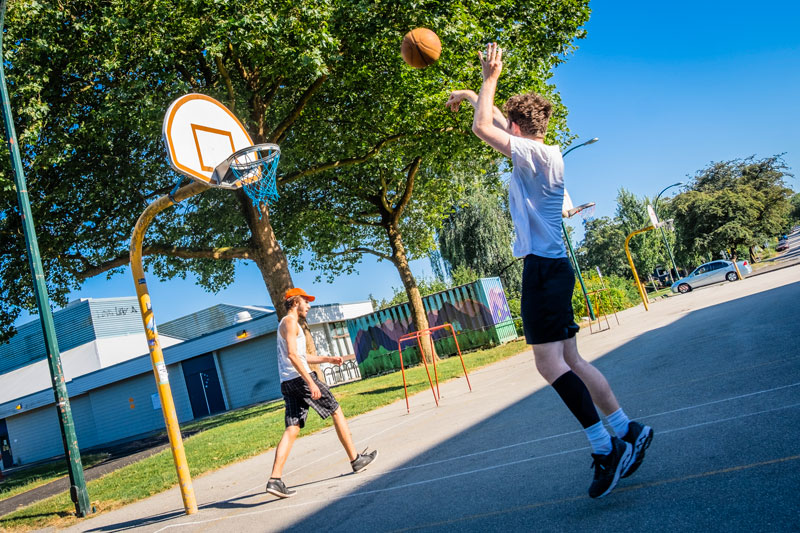 An image of two people playing basketball, with one person jumping to make a shot