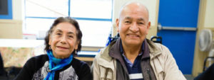 An indoor image of two seniors smiling together