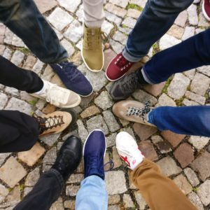 An image of people wearing all different shoes, with their feet meeting in a circle