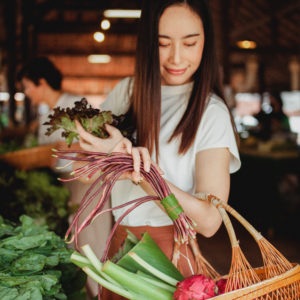 An image of a person placing vegetables in her basket at the market