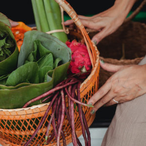 An image of a person holding a basket full of market veggies